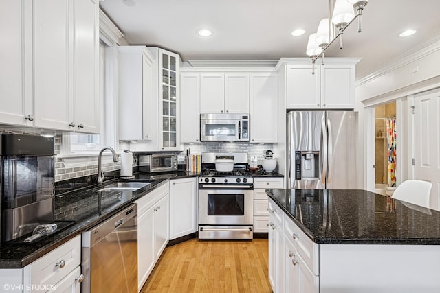 kitchen featuring appliances with stainless steel finishes, a sink, white cabinets, backsplash, and ornamental molding