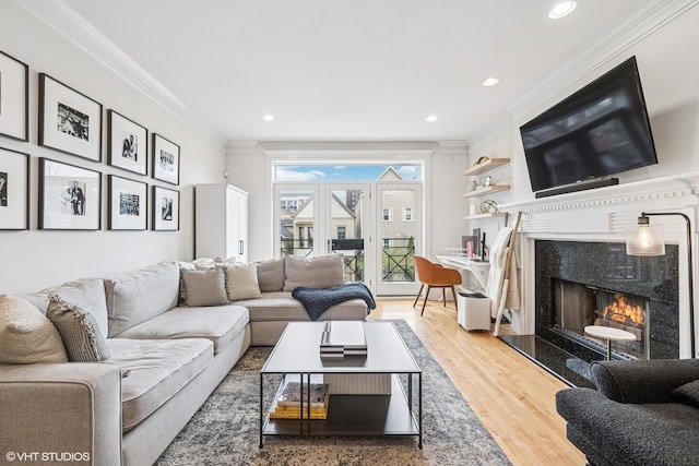 living area with crown molding, a high end fireplace, wood finished floors, and recessed lighting