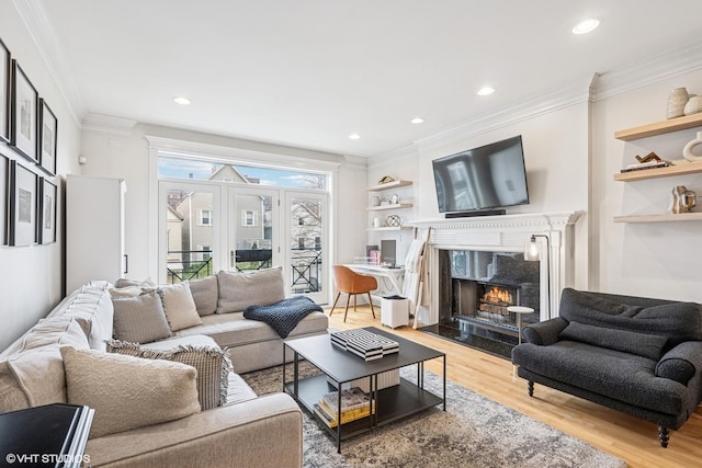 living room featuring wood finished floors, ornamental molding, built in shelves, a high end fireplace, and recessed lighting