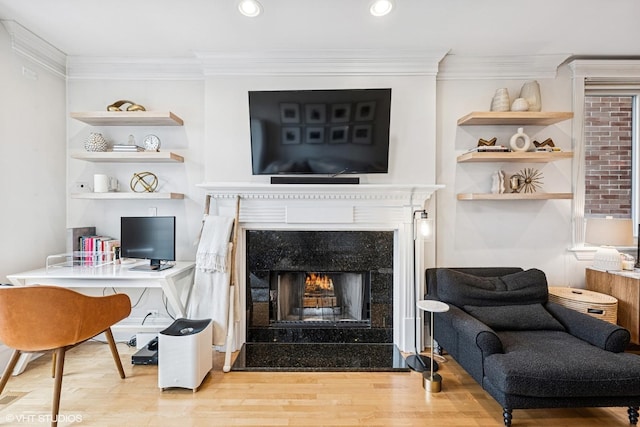 living area featuring wood finished floors, ornamental molding, a desk, a premium fireplace, and recessed lighting
