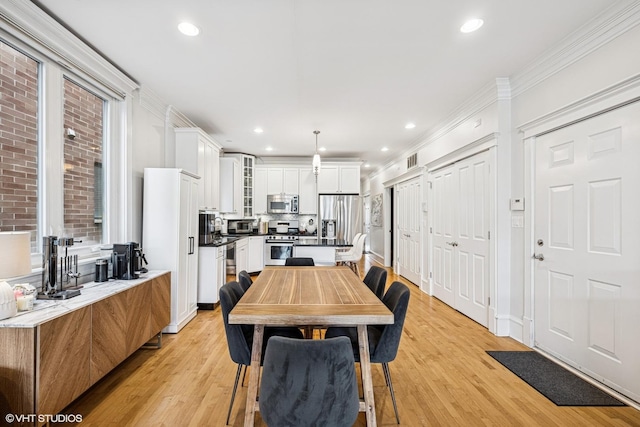 dining space with light wood-style flooring, recessed lighting, crown molding, and baseboards