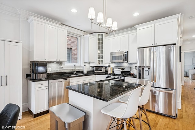 kitchen with appliances with stainless steel finishes, a sink, white cabinetry, ornamental molding, and recessed lighting