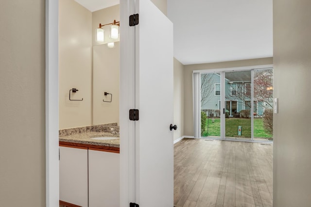 bathroom with baseboards, wood finished floors, and vanity