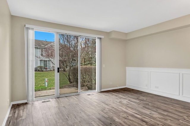 unfurnished room with visible vents, wainscoting, and wood finished floors