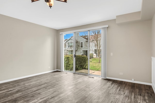 unfurnished room featuring dark wood finished floors, baseboards, visible vents, and ceiling fan