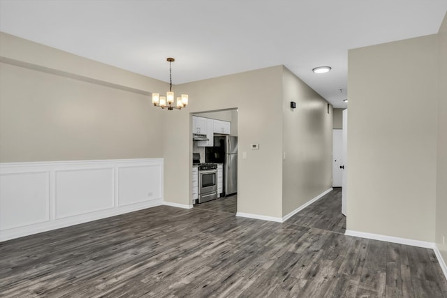 unfurnished room featuring baseboards, dark wood-style flooring, and an inviting chandelier