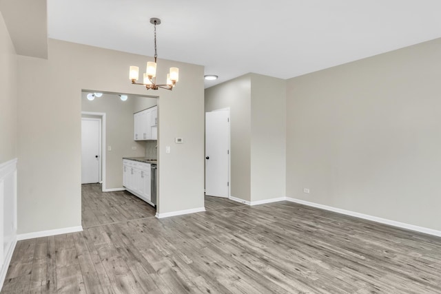 interior space with light wood-style flooring, baseboards, and an inviting chandelier