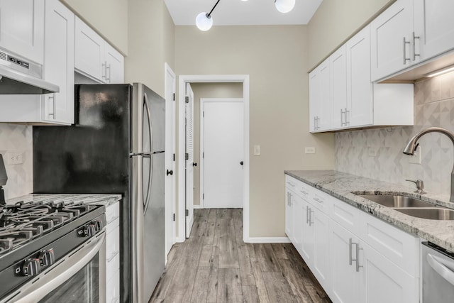 kitchen featuring wood finished floors, a sink, stainless steel appliances, white cabinetry, and under cabinet range hood