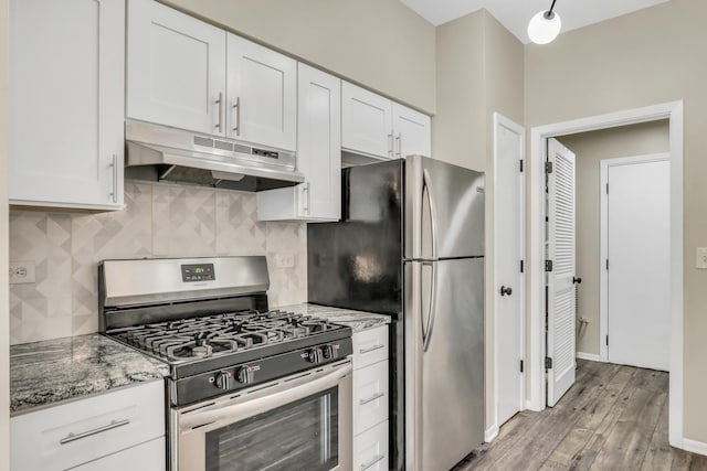 kitchen featuring under cabinet range hood, backsplash, light wood-type flooring, appliances with stainless steel finishes, and white cabinetry