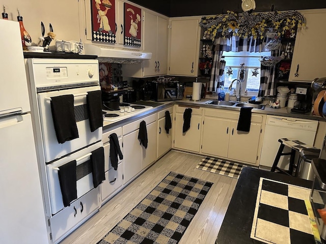 kitchen with white cabinets, a sink, light wood-type flooring, white appliances, and light countertops