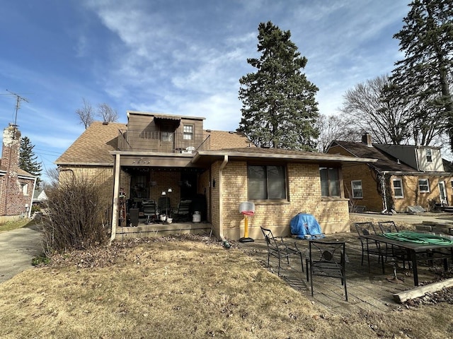 rear view of property with brick siding, a patio, and a shingled roof