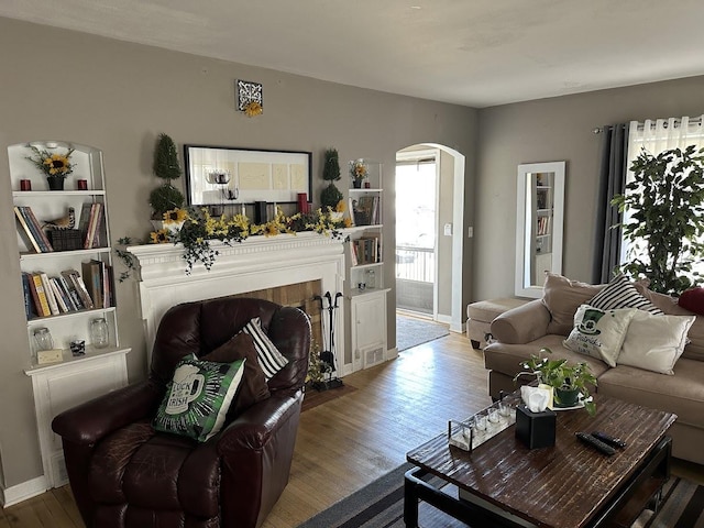 living room featuring arched walkways, wood finished floors, and baseboards