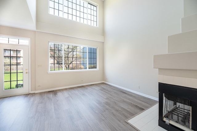 5464 Mayflower Jct, Rolling Meadows, IL 60008 - unfurnished living room featuring wood finished floors, a tiled fireplace, plenty of natural light, and baseboards