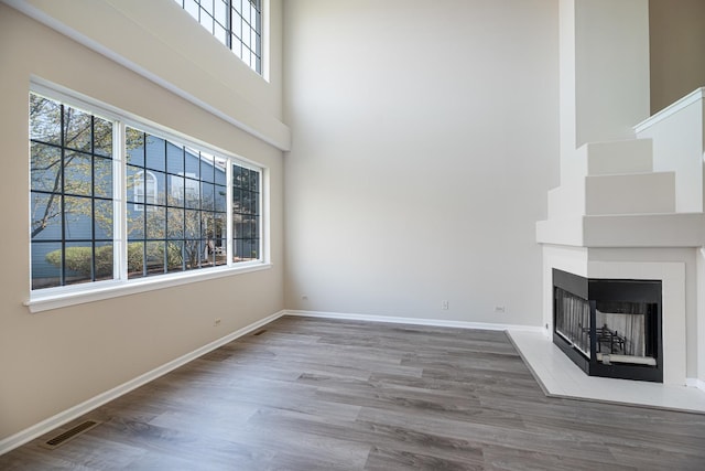 5464 Mayflower Jct, Rolling Meadows, IL 60008 - unfurnished living room with a multi sided fireplace, visible vents, baseboards, a towering ceiling, and wood finished floors