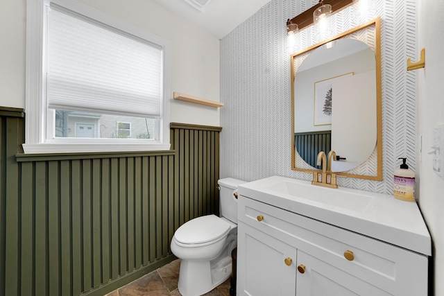 4240 Hearthstone Ln, Belvidere, IL 61008 - bathroom featuring wallpapered walls, toilet, stone finish flooring, wainscoting, and vanity