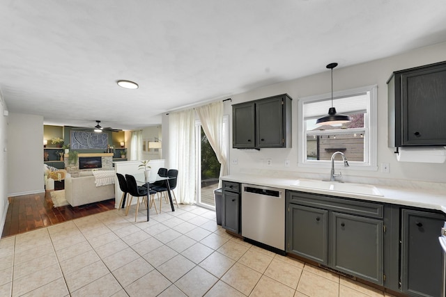 4240 Hearthstone Ln, Belvidere, IL 61008 - kitchen featuring a sink, dishwasher, open floor plan, light countertops, and a glass covered fireplace