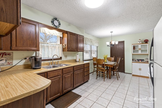 kitchen with light countertops, a sink, light tile patterned flooring, a chandelier, and a textured ceiling