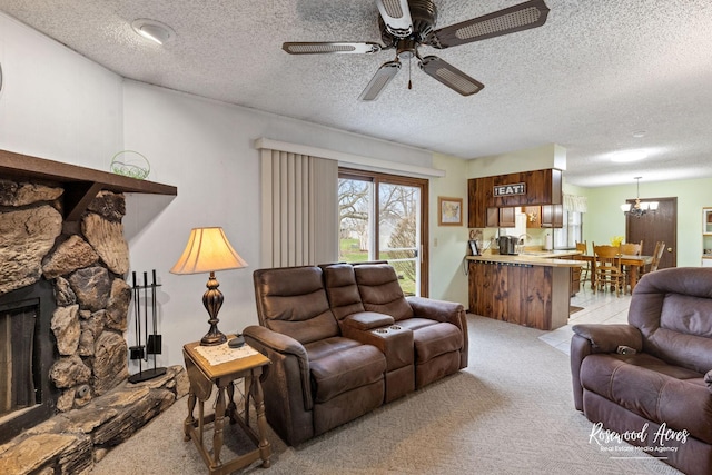 living room with a fireplace, a textured ceiling, light colored carpet, and ceiling fan with notable chandelier