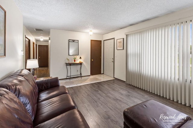 living room with wood finished floors, visible vents, and a textured ceiling