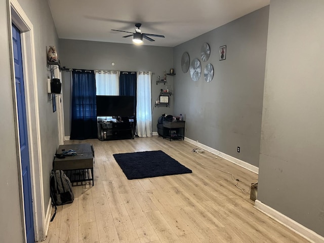 living room with ceiling fan, baseboards, and wood finished floors