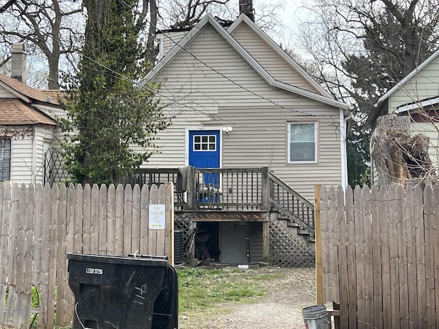 back of house with fence, a deck, and stairway
