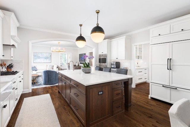 kitchen featuring dark brown cabinetry, backsplash, light countertops, stainless steel appliances, and white cabinetry