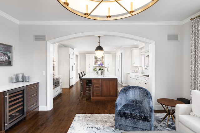 interior space with ornamental molding, dark wood-type flooring, beverage cooler, and visible vents