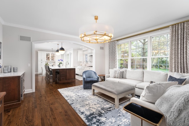 living room with an inviting chandelier, visible vents, ornamental molding, dark wood-type flooring, and arched walkways