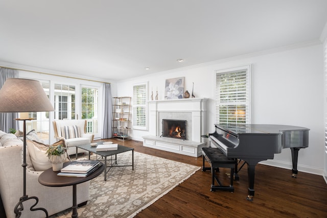 living area with baseboards, ornamental molding, dark wood finished floors, and a warm lit fireplace