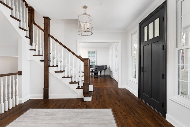 entrance foyer featuring an inviting chandelier, stairs, baseboards, wood finished floors, and ornamental molding