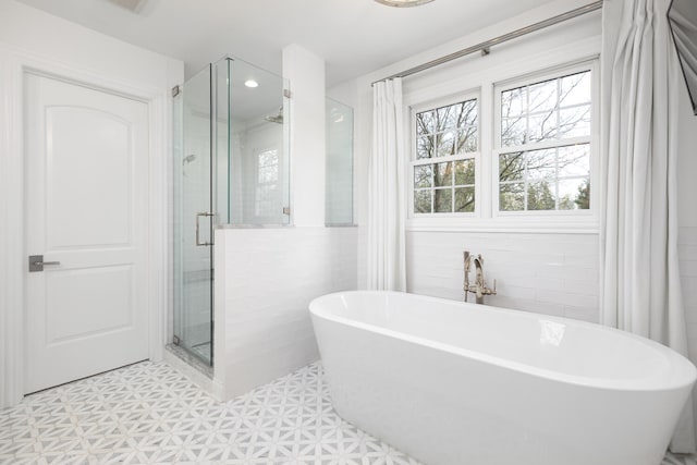 bathroom with a freestanding bath, tile walls, a shower stall, and tile patterned floors