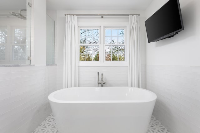 full bath with a freestanding bath, tile walls, and wainscoting