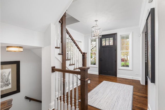 entryway featuring a notable chandelier, dark wood finished floors, baseboards, ornamental molding, and stairway