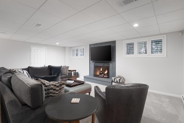 carpeted living area with baseboards, a fireplace, a paneled ceiling, and visible vents