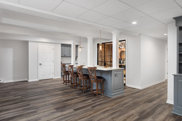 kitchen featuring a kitchen breakfast bar, dark wood finished floors, gray cabinets, recessed lighting, and baseboards