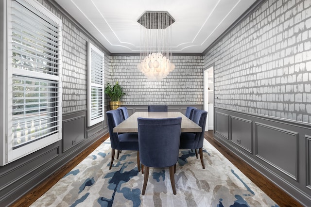 dining room featuring crown molding, wainscoting, wood finished floors, an inviting chandelier, and wallpapered walls