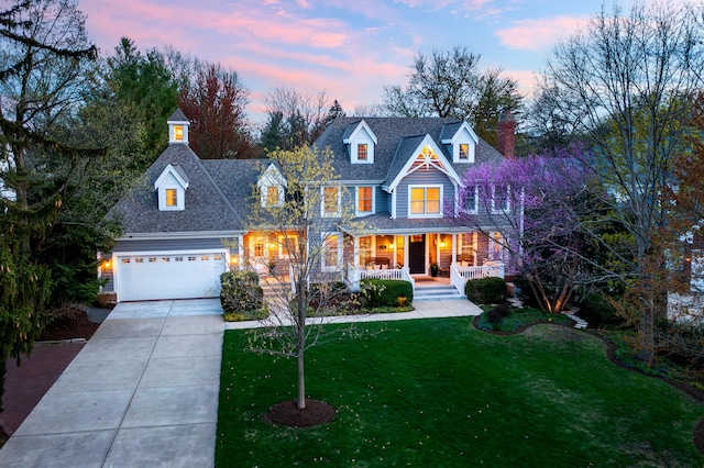 view of front of house with an attached garage, a chimney, a lawn, covered porch, and driveway
