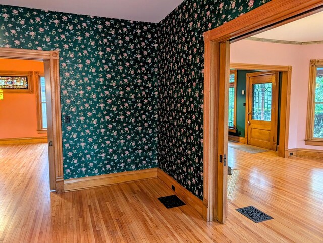 907 W Church St, Champaign, IL 61821 - empty room featuring wallpapered walls, wood finished floors, baseboards, and ornamental molding