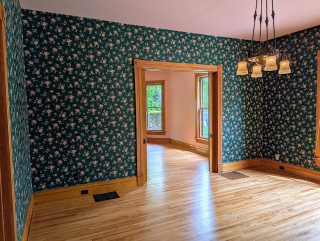 907 W Church St, Champaign, IL 61821 - unfurnished dining area featuring wallpapered walls, wood finished floors, baseboards, and a chandelier
