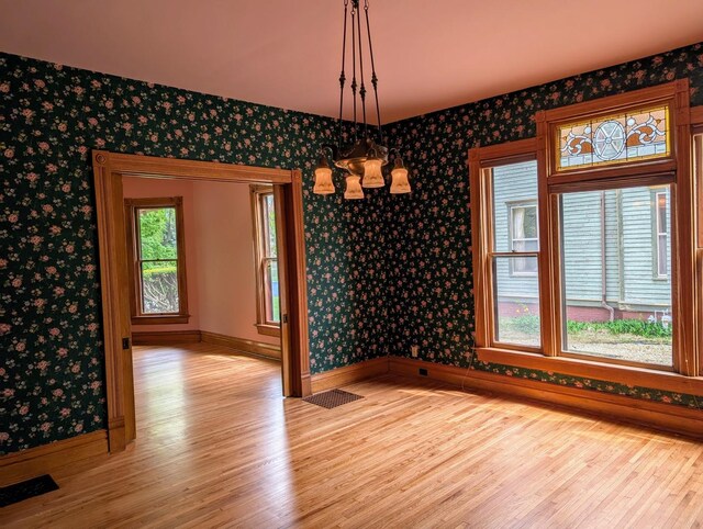 907 W Church St, Champaign, IL 61821 - unfurnished dining area with wallpapered walls, baseboards, wood finished floors, and a chandelier