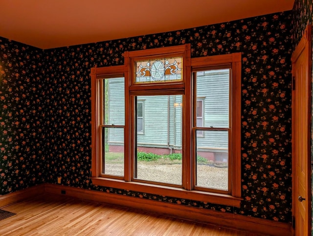 907 W Church St, Champaign, IL 61821 - spare room featuring wallpapered walls, wood finished floors, and baseboards