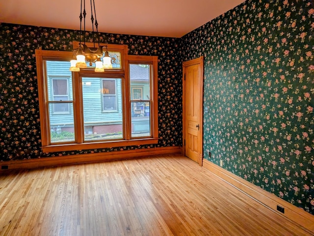 907 W Church St, Champaign, IL 61821 - unfurnished dining area with wallpapered walls, baseboards, wood finished floors, and a chandelier