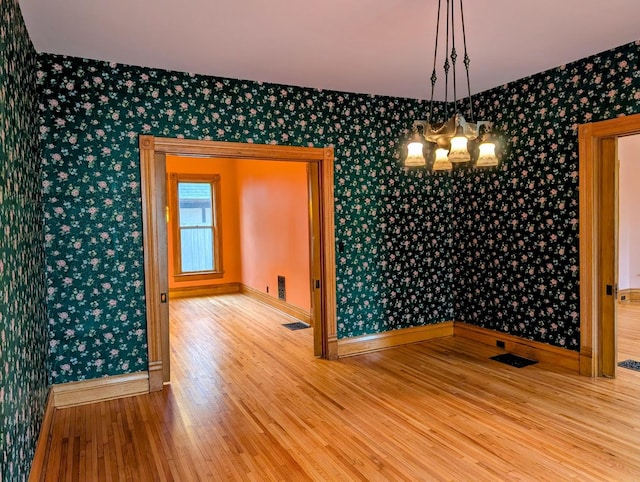 907 W Church St, Champaign, IL 61821 - empty room with wallpapered walls, wood finished floors, a chandelier, and baseboards