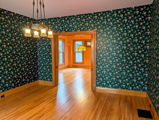 907 W Church St, Champaign, IL 61821 - unfurnished dining area featuring wallpapered walls, wood finished floors, baseboards, and a chandelier