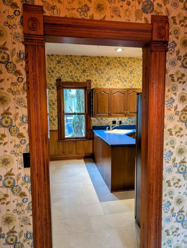 907 W Church St, Champaign, IL 61821 - kitchen featuring wallpapered walls, brown cabinetry, decorative columns, and a sink