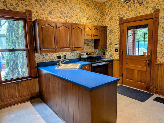 907 W Church St, Champaign, IL 61821 - kitchen featuring electric stove, a sink, a peninsula, plenty of natural light, and wallpapered walls