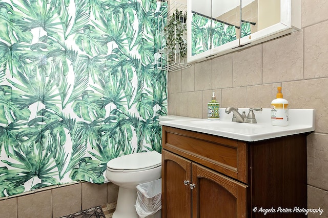 bathroom with tasteful backsplash, tile walls, toilet, and vanity