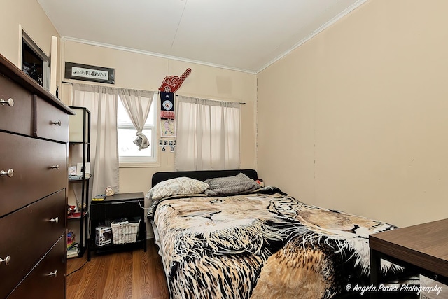 bedroom with ornamental molding and wood finished floors