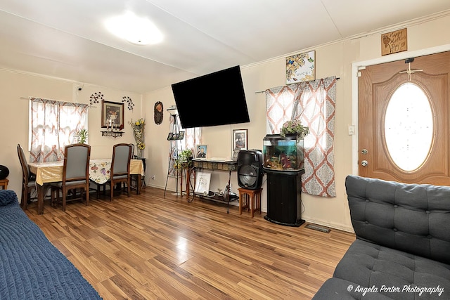 living area with light wood finished floors, visible vents, and crown molding