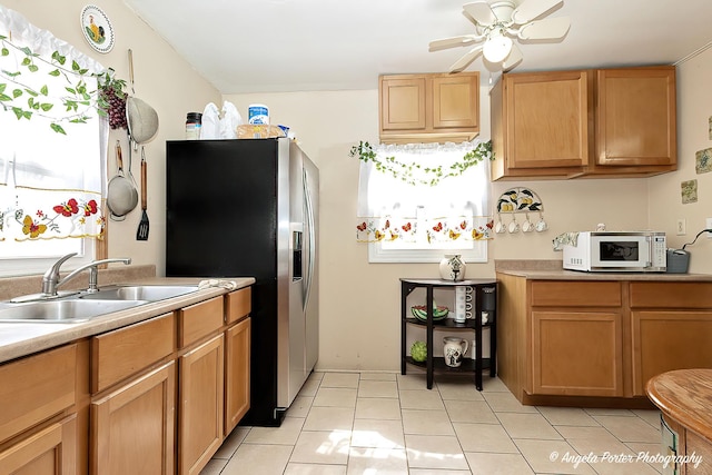 kitchen featuring a sink, light tile patterned floors, ceiling fan, stainless steel fridge with ice dispenser, and light countertops